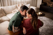 © Studio Dva Kera - Young couple sharing a kiss in their living room.