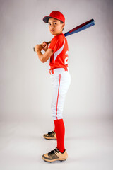 Wall Mural - Young teenage baseball player model in baseball uniform standing in studio with white background