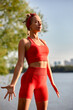 © Georgii - A woman is engaged in animal flow gymnastics, close-up outdoors near the river on green grass in red clothes.