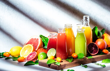 Wall Mural - Summer beverages. Citrus fruit juices, fresh and smoothies, food background. Mix of different whole and cut fruits: orange, grapefruit, lime, tangerine with leaves and bottles with drinks