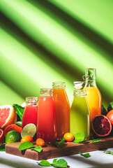 Wall Mural - Summer drinks. Citrus fruit juices, fresh and smoothies, food background. Mix of different whole and cut fruits: orange, grapefruit, lime, tangerine with leaves and bottles with beverages