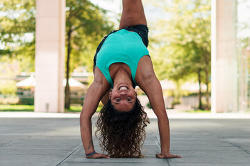 linda mujer morena practicando ejercicios y capoeira en la ciudad sonriendo.