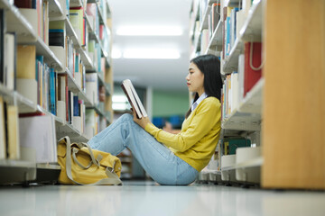 Poster - Student sitting on the floor and reading at library.