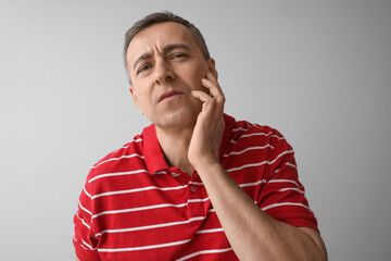 Canvas Print - Tired mature man in red t-shirt on grey background, closeup