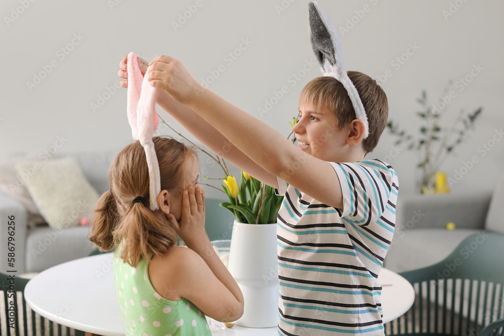 Little boy and his sister with bunny ears in kitchen