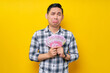 © Bangun Stock Photo - Portrait of crying young Asian man wearing plaid shirt holding cash money in rupiah banknotes and thrilled to get money isolated on yellow background. people lifestyle concept