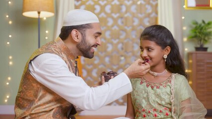 Wall Mural - Happy smiling muslim father feeding dates to daughter during ramadan dining feast festival celebration at home - concept of ramazan feast, relationship and healthy eating