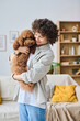 © AnnaStills - Vertical image of young woman holding dog in her arms and embracing it while standing in the room