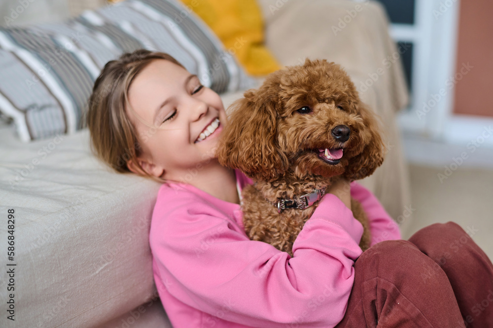 Happy little girl playing with her dog, she sitting on the floor in the ...
