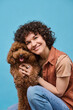 © AnnaStills - Portrait of young happy woman embracing her dog and smiling at camera isolated on blue background
