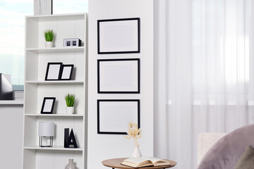 Poster - Stylish room interior with empty frames hanging on white wall near shelving unit