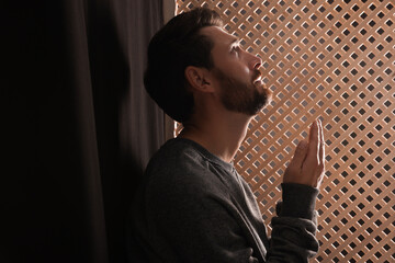 Wall Mural - Man praying to God during confession in booth