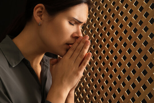 Wall Mural - Woman praying to God during confession in booth