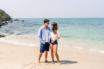 Wall Mural - Vacation romantic love young happy smile couple in honeymoon travel holiday trip standing on sand at blue sky sea beach having fun and relaxing together on tropical beach.Summer travel