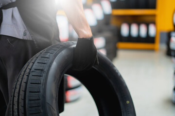 A mechanic holding a tire in a tire warehouse of a car service center