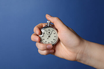 Wall Mural - Woman holding vintage timer on blue background, closeup