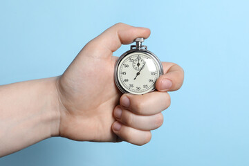 Wall Mural - Man holding vintage timer on light blue background, closeup