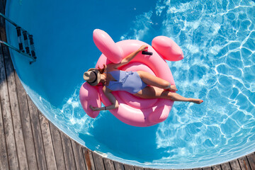 Wall Mural - Woman relaxing on pink flamingo inflatable ring