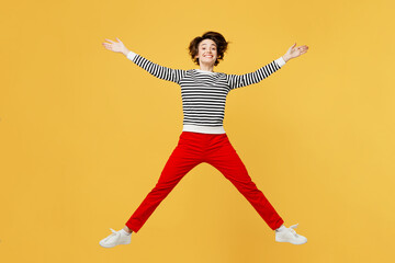 Wall Mural - Full body excited happy fun cheerful young woman wearing casual black and white shirt jumping high with outstretched hands isolated on plain yellow color background studio portrait. Lifestyle concept.