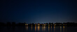 Flussufer mit Stadtsilhouette bei Nacht 