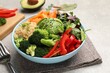 © New Africa - Delicious vegan bowl with bell peppers, avocados and broccoli on table, closeup