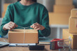 © Kritdanai - Startup small business entrepreneur or freelance Asian woman using a laptop with box, Young success Asian woman with her hand lift up, online marketing packaging box and delivery, SME concept.