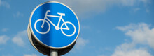 Round Road Sign Depicting White Bicycle On Blue Background, Meaning Mandatory Bike Path For Cyclists Against Blue Sky Background. Blue Round Sign On Bike Path Pole. Bike Path