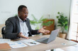 © Jirapong - african american man, video call and laptop, wave hello and meeting, consulting or internet planning in startup company. Happy worker greeting for online meeting, computer webinar