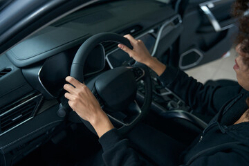 Wall Mural - Curly-haired woman sits behind wheel in interior of modern car