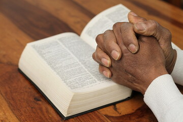 praying to God with hand on the bible on black background stock photo	