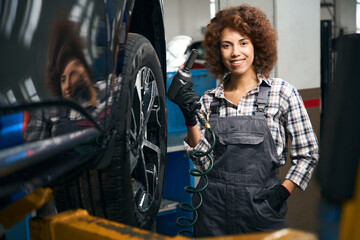 Canvas Print - Cute woman repairman holds a pneumatic screwdriver in her hands