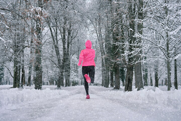 Wall Mural - Running woman, girl runner on snow in park in winter sunny day.