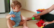 Mother showing baby to play with puzzle toys at home indoors