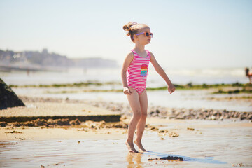 Canvas Print - Preschooler girl having fun on the sand beach at Atlantic coast of Normandy, France