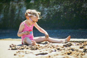 Sticker - Preschooler girl playing on the sand beach at Atlantic coast of Normandy, France