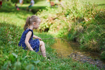 Preschooler girl playing with a twig like with fishing rod