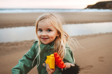 Child girl walking on the beach outdoor family lifestyle vacations girl happy smiling playing with toys