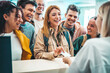 © Davide Angelini - Group of young people takes room key card at check-in of youth hostel guest house - Happy tourists talking with receptionist at hotel lobby - Summer vacations and tourism concept