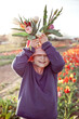 Young preteen girl stretching bunch of tulips to the camera, sunset outdoor scene.