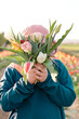 Young teenager girl hiding behind a bunch of tulips. Sunset outdoor scene, family outdoor activity time