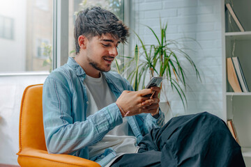 Wall Mural - young man with mobile phone or smartphone on the sofa at home