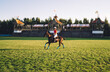 Horsewoman in polo equipment riding on playing field