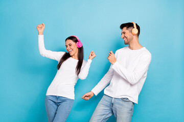 Poster - Portrait of two satisfied positive funny persons dressed white shirts dancing having fun enjoy music isolated on blue color background