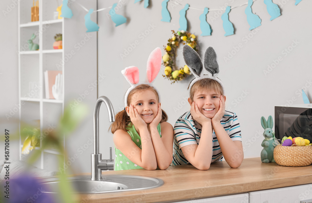 Little children with bunny ears in kitchen on Easter day