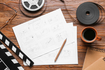 Storyboard with movie clapper, film reel and cup of coffee on wooden background
