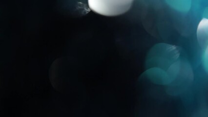 Wall Mural - Slow Motion Of Light Blue Bokeh On Black Background. Blue and White glow defocused circle lights background. Abstract moving background, overlay or transition in 4K.