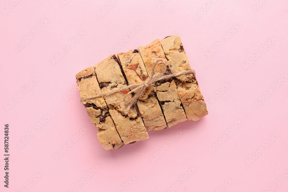 Delicious biscotti cookies tied with thread on pink background
