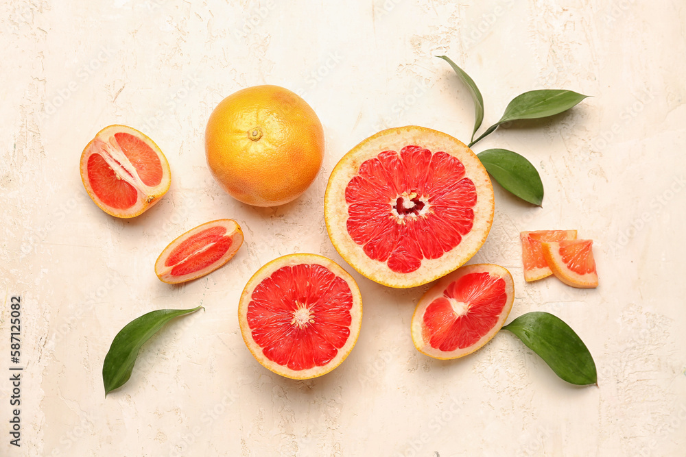 Composition with juicy grapefruit pieces and plant leaves on light background
