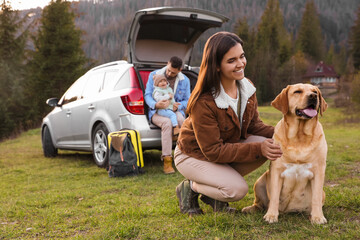 Canvas Print - Happy woman with dog, father and his daughter sitting in car trunk outdoors. Family traveling with pet