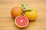 Fototapeta Kuchnia - Fresh ripe grapefruits, flowers and green leaves on wooden table